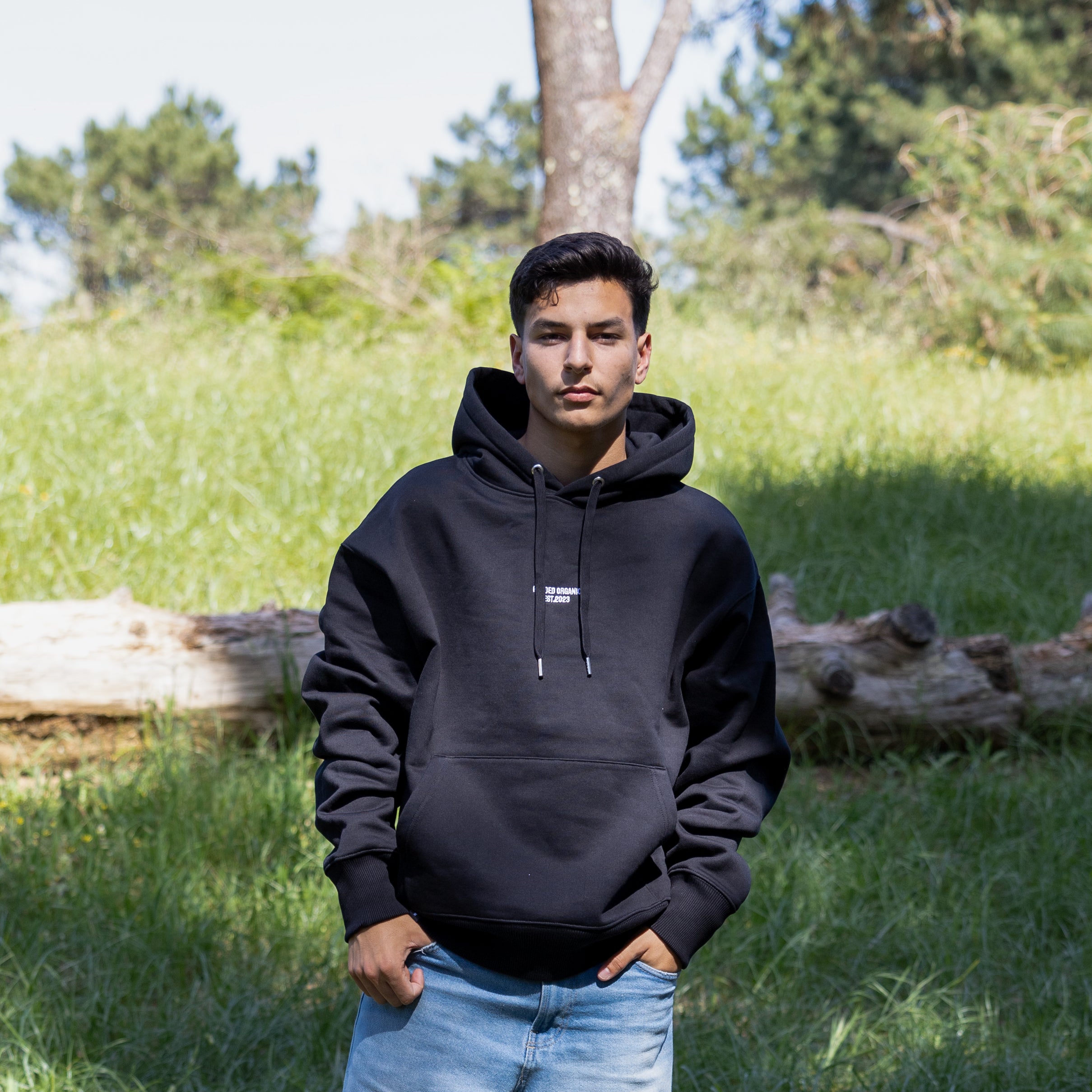 Mandelig model i sort hoodie med hætten nede set forfra – dansk design i 100% økologisk bomuld

