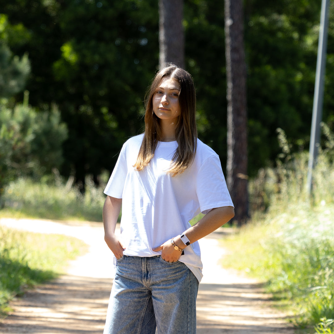 Kvindelig model i hvid økologisk T-shirt i skoven – GOTS-certificeret dansk design og bæredygtig stil